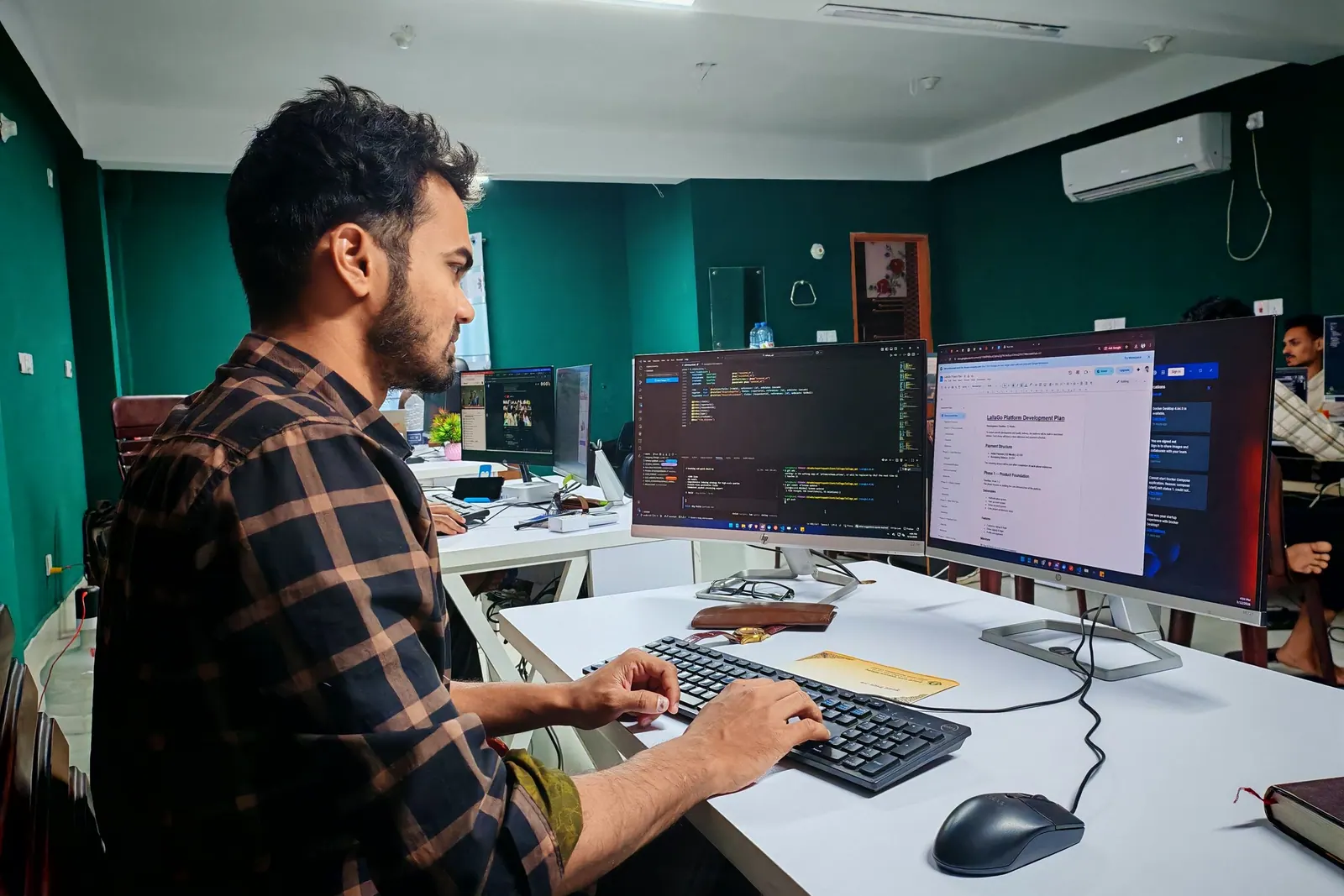 A contractor at a desk with two monitors