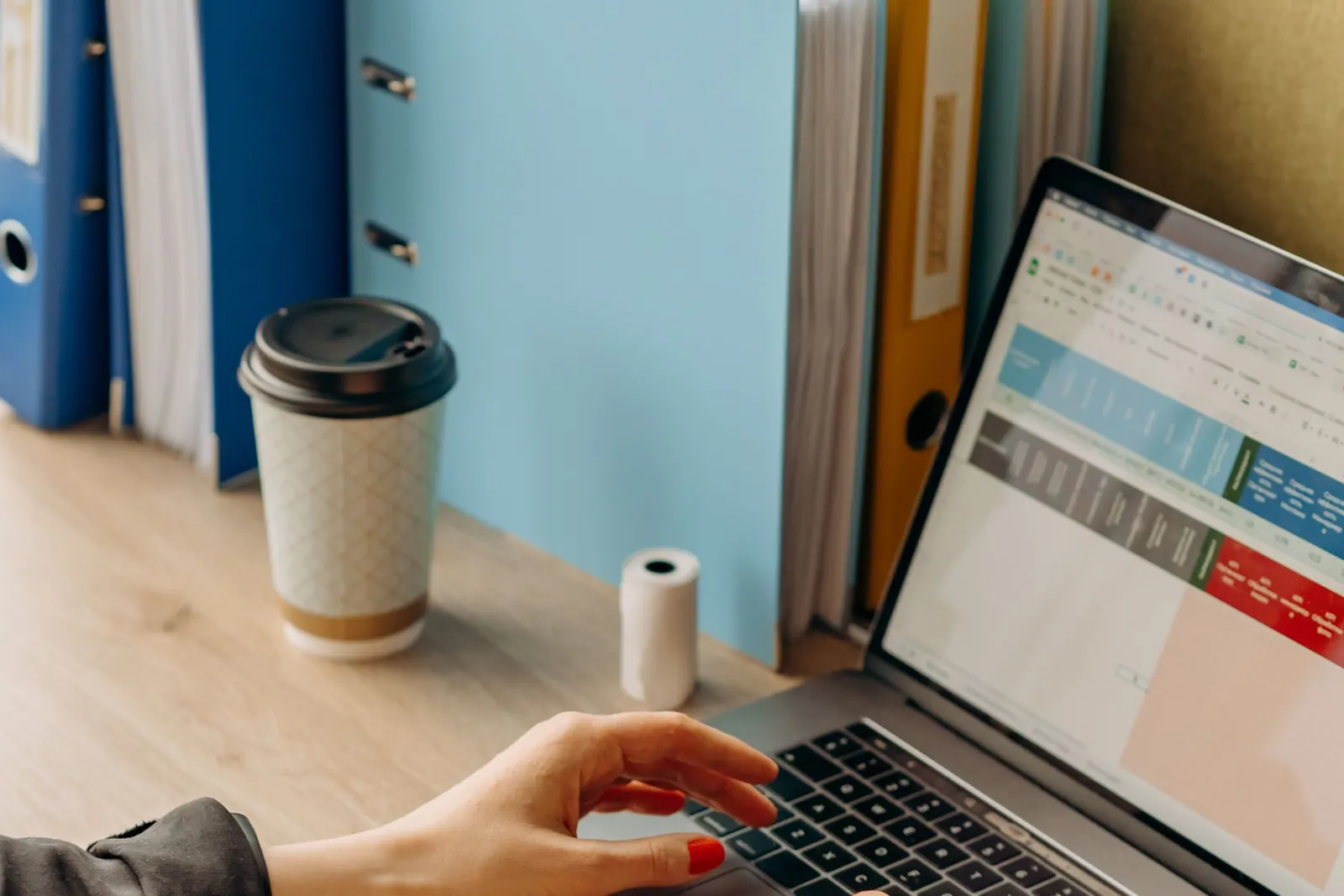 A colour-coded spreadsheet open on a laptop on an office desk