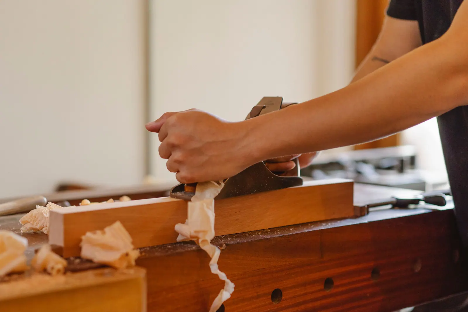Hands working a piece of wood on a workbench in a small production workshop