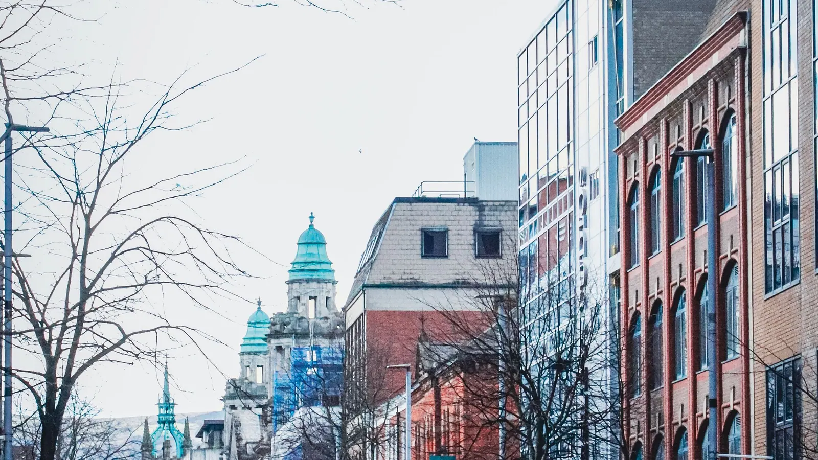 Victorian street in Belfast with City Hall's domes visible above the rooftops